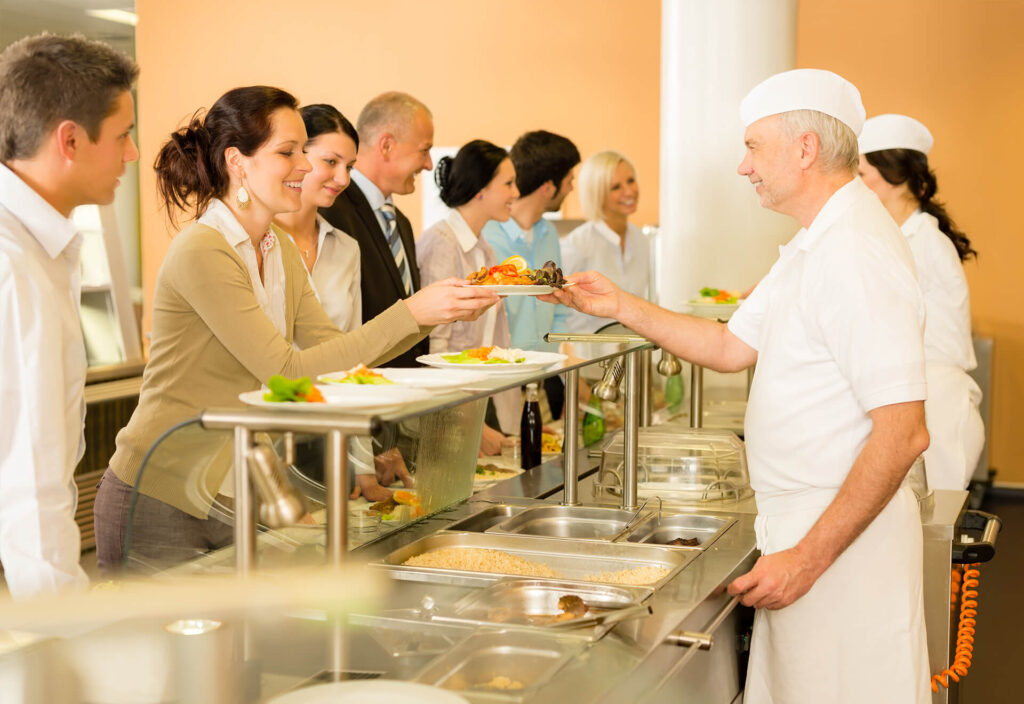 Kantinenpersonal gibt Essen an Kundin aus