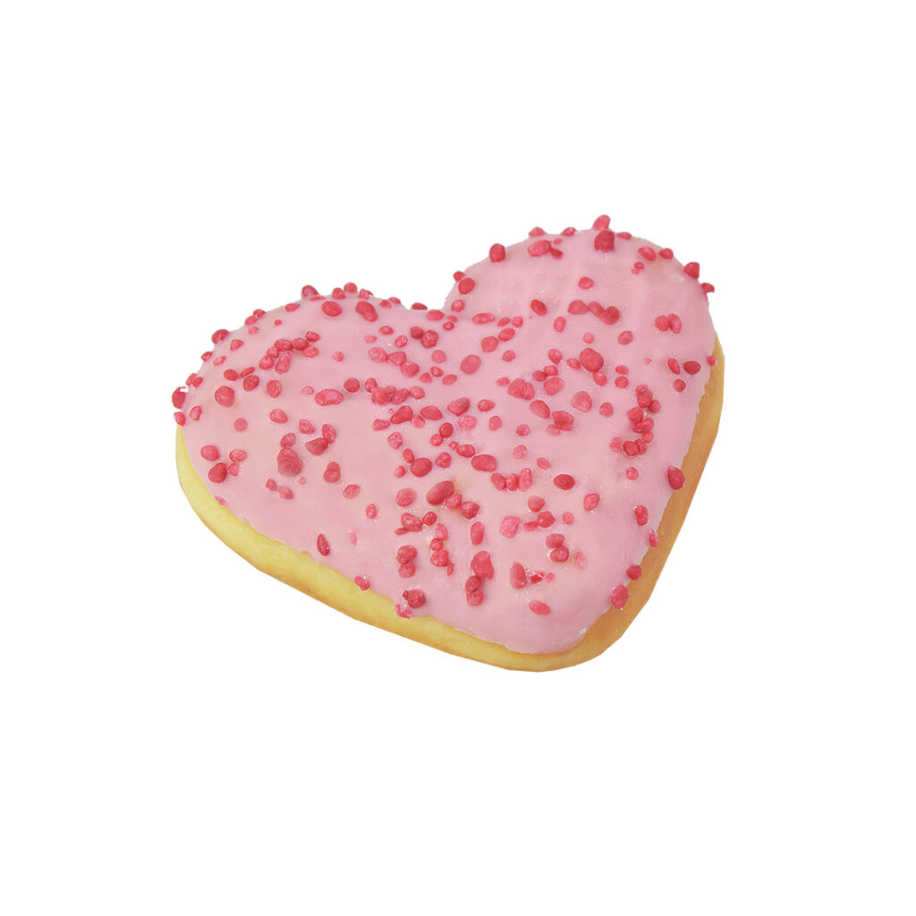 Herzförmiger Donut mit rosa Zuckerguss und roten Streuseln.
