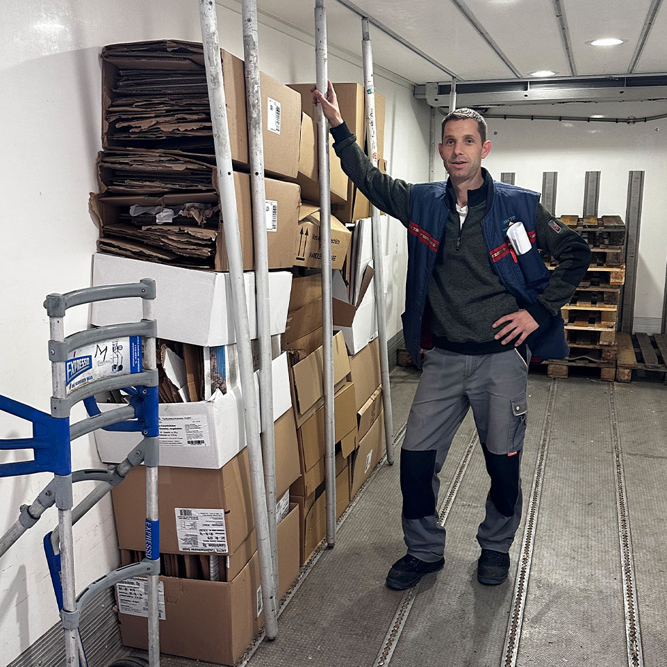 Mitarbeiter steht in LKW mit zu Kartons zum Recyclen